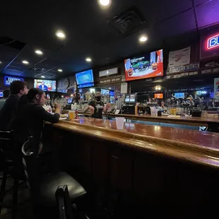 people sitting at the bar watching televisions