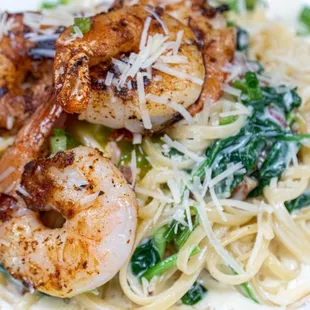 a plate of pasta with shrimp and spinach