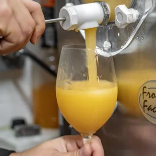 a person pouring orange juice into a glass