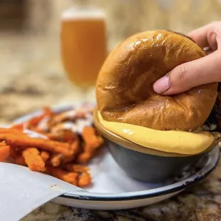 a person grabbing a hamburger from a plate