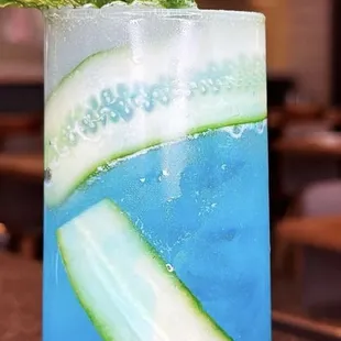 a blue drink with cucumber and mint