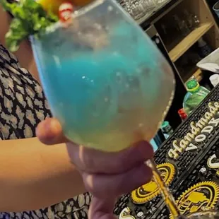 a woman holding a blue cocktail