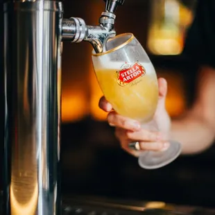 a person pouring a beer at a bar
