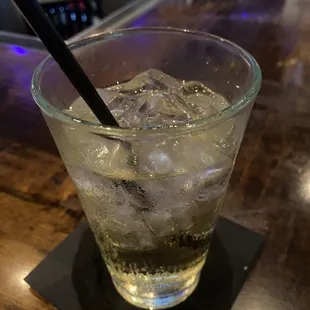 a glass of ice water with a black straw