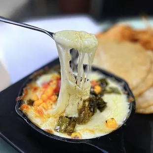 Queso Fundido w/ monterey jack cheese, cilantro, peppers, corn chips or chicharrónes | $9