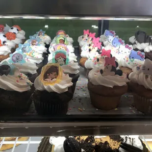 Dark and light brown muffins with white frosting, decorated with animated movie and TV show character faces.