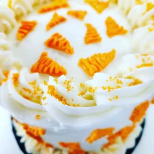 a carrot cake with white frosting and orange sprinkles
