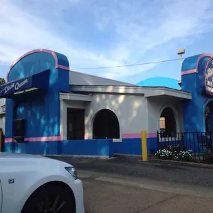 a white car parked in front of a blue building