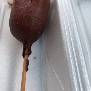 a chocolate covered donut on a stick