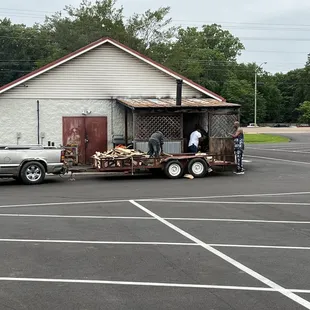 two men loading a truck with a trailer full of wood