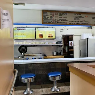 a restaurant counter with two blue stools