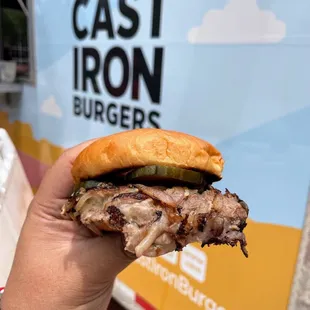 a hand holding a pulled pork sandwich