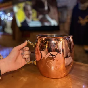 a hand holding a copper mug