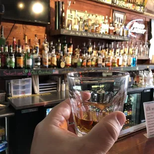 a hand holding a shot of whiskey