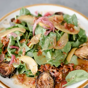 a plate of salad with spinach and bacon