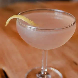 a pink cocktail with a lemon garnish