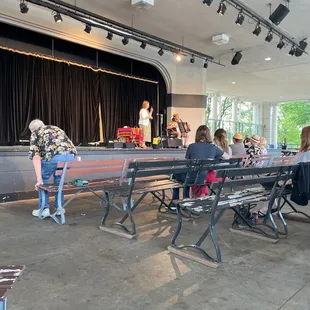 a group of people sitting on benches in front of a stage