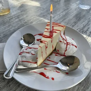 a slice of cheesecake with a lit candle