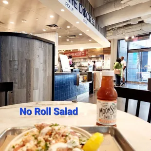 a bowl of salad and a bottle of hot sauce