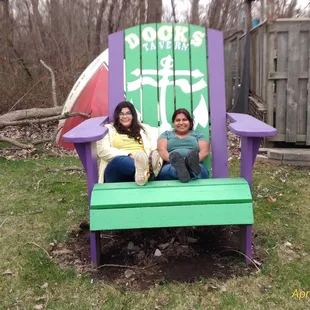 two women sitting in a purple and green chair