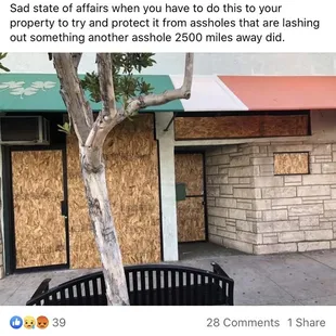 a tree in front of a boarded building
