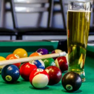 a pool table with billiards and a beer