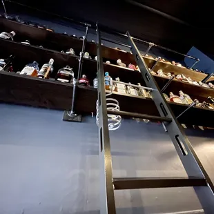 a ladder leading to a shelf full of liquor bottles