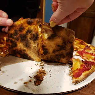 a person taking a slice of pizza