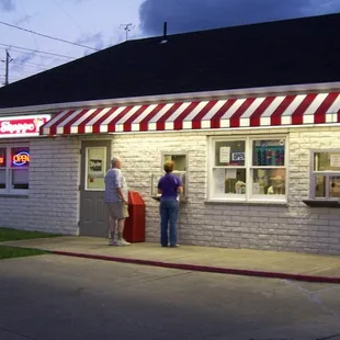 two people standing outside of a diner
