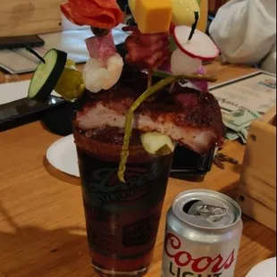 Large bloody mary drink with several food items on top