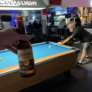 a pool table with a bottle of corona light