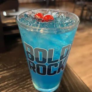 a blue drink with a cherry in it