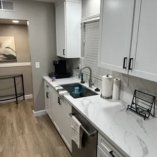 a kitchen with white cabinets and marble countertops