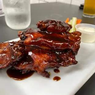 a plate of chicken wings with sauce and carrots