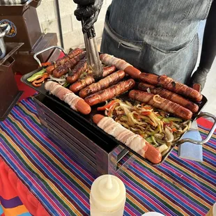 a man cooking hot dogs on a grill