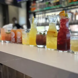 a row of different drinks on a bar