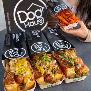 a woman holding a box of dog haus