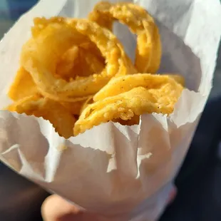 a person holding a bag of fried onion rings