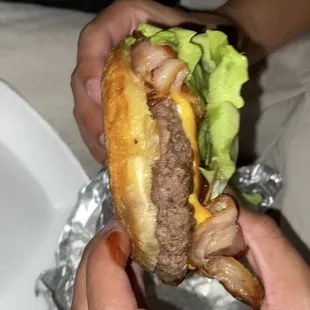 a person holding a hamburger in their hands