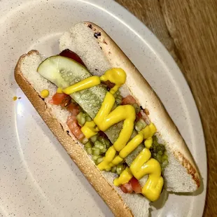 a hot dog with mustard and pickles