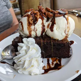 a slice of chocolate cake with ice cream and pecans