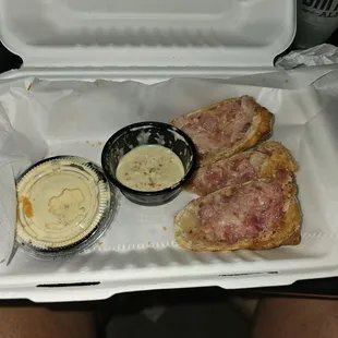 a styrofoam container with a sandwich and dips