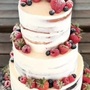 Custom three tier wedding cake topped with fresh fruit.