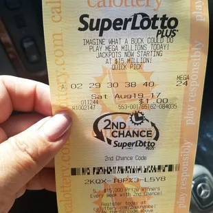 a hand holding a superlot ticket