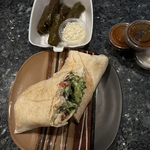 a burrito and pickles on a plate
