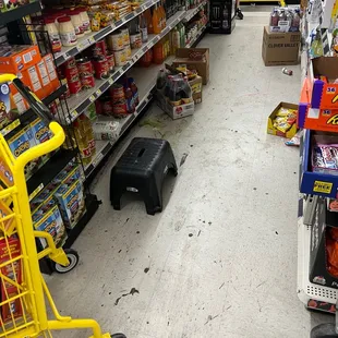Trash, dirty floor, step stool, and product along with random carts just blocking not being used by customers