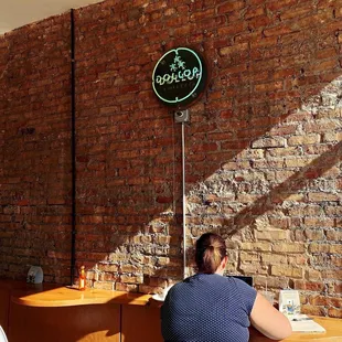 a woman sitting at a table in front of a brick wall