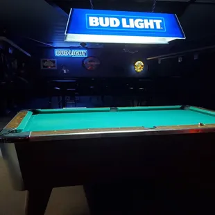 a pool table with a bud light sign above it