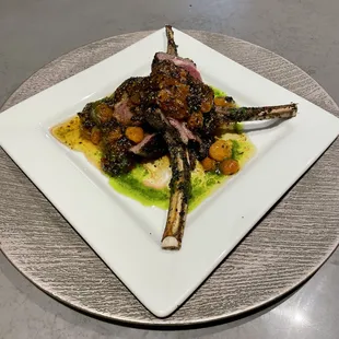 a plate of lamb chops and vegetables