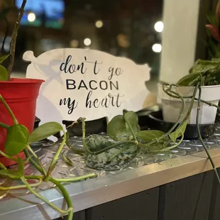 a bunch of potted plants and a sign that says don't let bacon in my heart